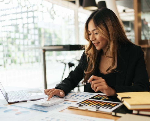 Business Person With Calculator Looking At Charts And Graphs