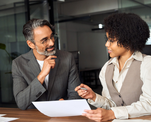 Two Business People Looking At Paperwork In Office